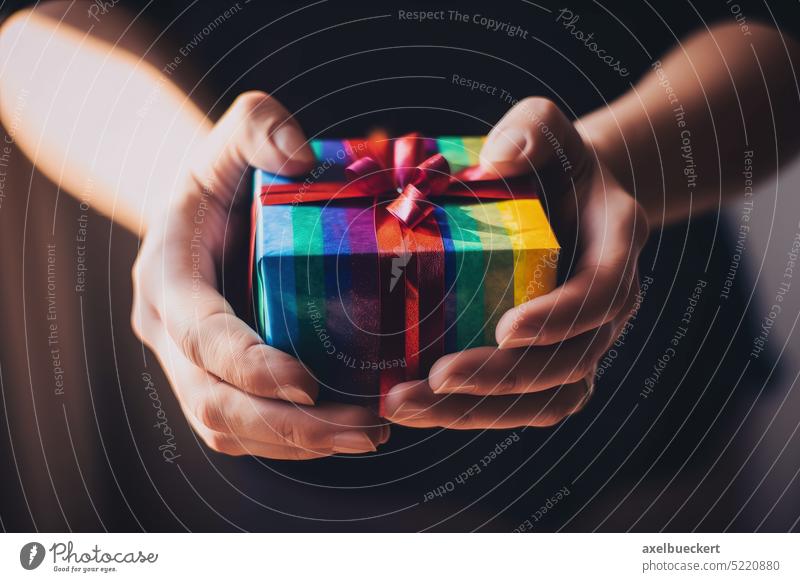 Hands holding rainbow colored lgbt present or gift box. Generative AI. lgbtq gay valentine pride birthday anniversary give receive giving receiving ribbon
