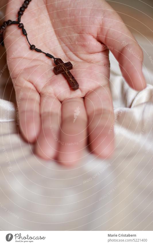 A wooden rosary and crucifix on an open palm of a hand representing lent, solemn Christian religious observance christian symbol faith belief hope devotion