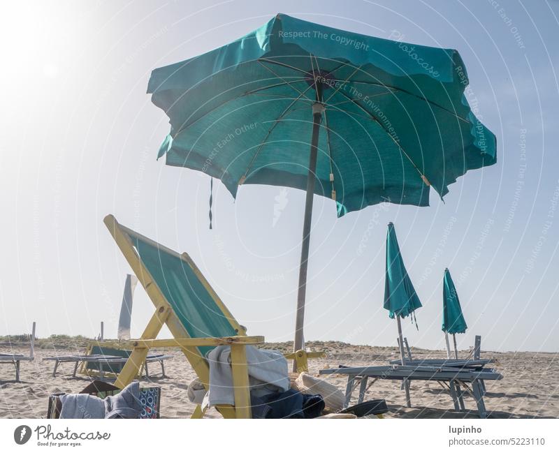 Deck chairs with umbrellas on secluded beach Beach Lonely recliner Opened parasols Closed Sand Sun morning Europe Italy vacation Exterior shot travel Sky clear