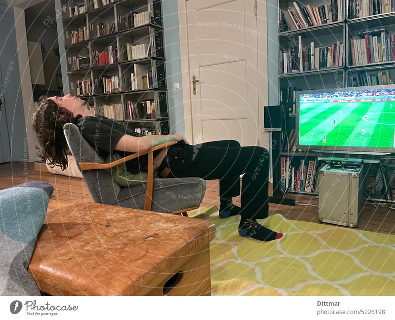 Exhausted young man on armchair misses soccer match Young man Sleep Armchair Living room TV soccer game Miss out