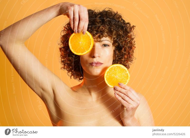 Adult woman with pieces of fresh orange cover face beauty routine slice citrus serious natural color bright female adult ripe wellness organic product vitamin c