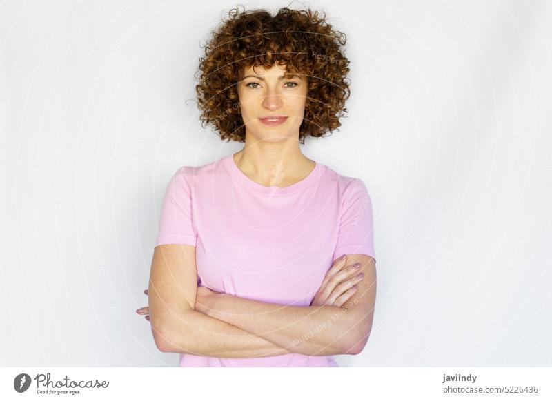 Adult woman with curly hair and crossed arms against white background confident arms crossed self confident hands crossed studio arms folded studio shot posture