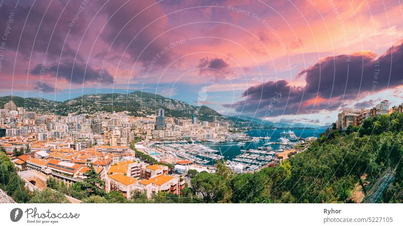 Monaco, Monte Carlo cityscape. Real estate architecture on mountain hill background. Many high-rise buildings in downtown area. Yachts moored at town quay In Sunny Summer Day. Altered Sunset Sky