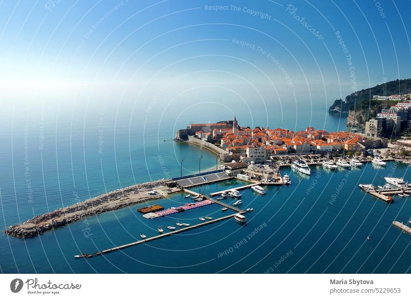 Aerial drone view of the ancient city of Budva on sunny day. Old medieval city with red roofs in Montenegro on the sunset. budva port aerial sea sky blue