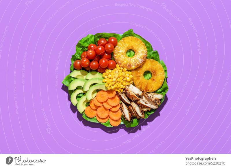 Hawaiian salad plate above view on purple background. Salad with roasted pineapple avocado bright carrot cherry chicken color corn cuisine cut out delicious