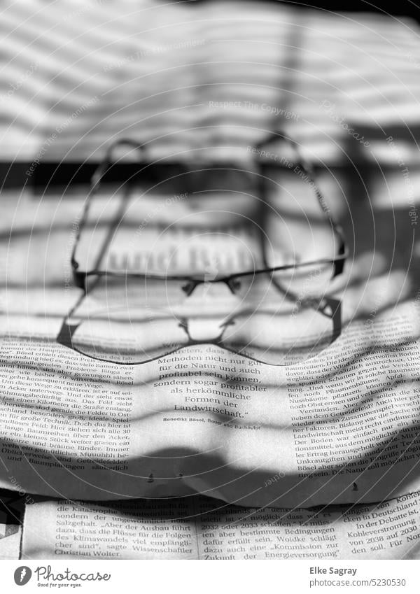 Shadow play glasses on newspaper with shadow cast Light Contrast Light and shadow Abstract Silhouette Black Structures and shapes Deserted