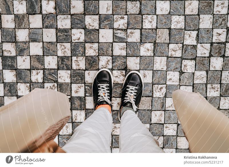 Female legs in sneakers on paving stones. Woman feet top view. Prague street abstract adult background black block brick city construction detail fashion floor