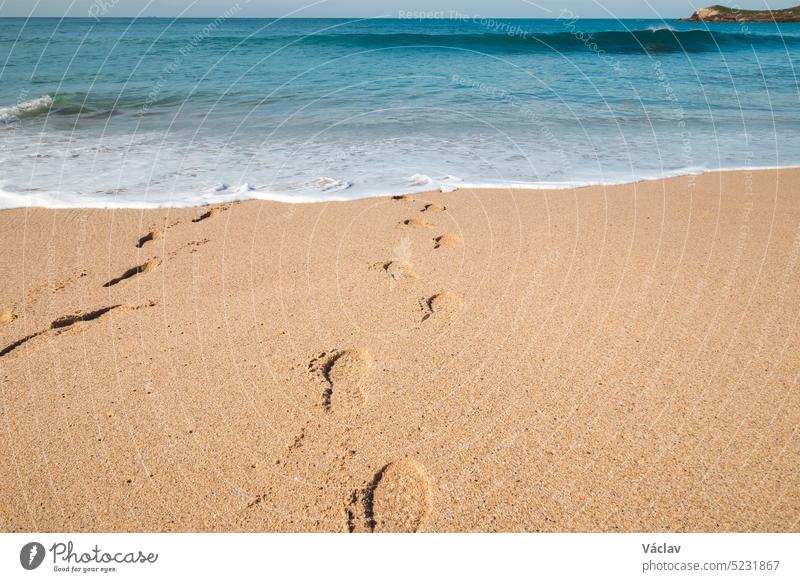 Footprints in the sand from a man sinking into the deep Atlantic Ocean on the sandy beach of Praia da Ilha do Pessegueiro near Porto Covo, western Portugal