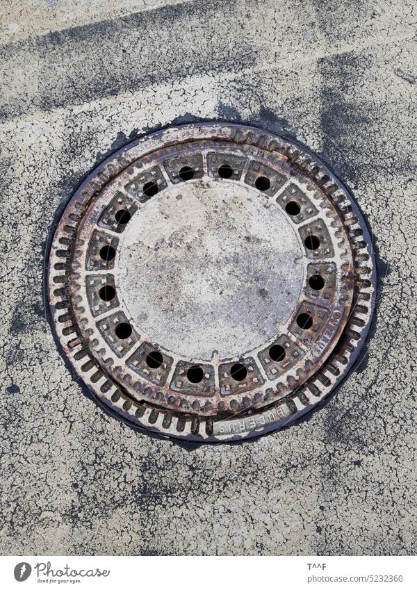 Rusty manhole cover in artistically designed asphalt walkway Channel Manhole cover lid Closure off Footpath Park Asphalt asphalt road Painted Gewegkunst rusty