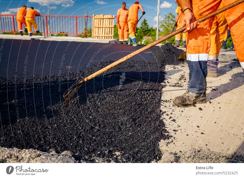 Workers are using shovels for realign hot asphalt to correct measure Adjust Align Alignment Asphalt Asphalting Bitumen Blacktop Blacktopping Bridge