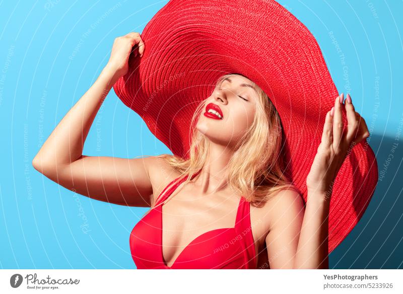 Beautiful blonde woman with oversized summer hat. Woman portrait in bright light background beach beauty big blue brim chic closed eyes color concept cool