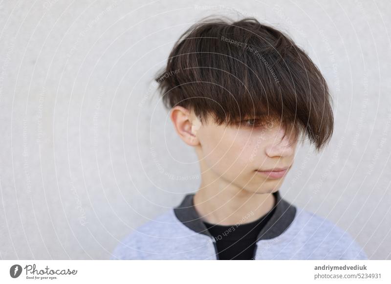 Handsome young man with stylish haircut. Portrait of teen boy with youth hairstyle is standing on grey background. face handsome lifestyle male model attractive