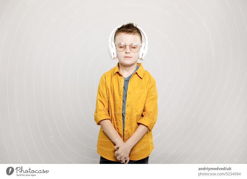 adorable child boy in white headphones and glasses isolated on grey background casual childhood cute fun happy joy kid music person portrait fashion leisure