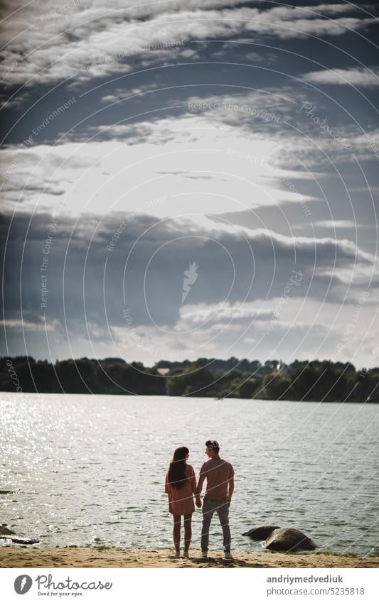 lovely couple stands by the water along river shore, holding hands together, happy family concept. love story beautiful lake man summer woman young care cute