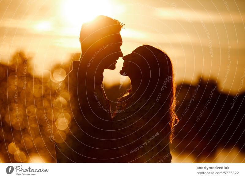 silhouette of loving couple hugging on the lake at sunset. Beautiful young couple in love walking on the shore of the lake at sunset in the rays of bright light. copy space. selective focus