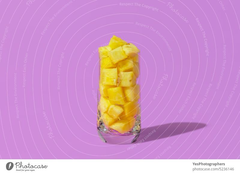 Pineapple juice concept. Glass with pineapple cubes isolated on a purple background ananas bright close-up color cuisine cut out delicious dessert diet food