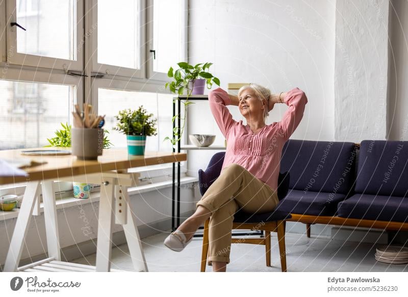 Relaxed senior woman sitting at the table in the office real people indoors loft window home mature adult one person attractive successful confident beautiful