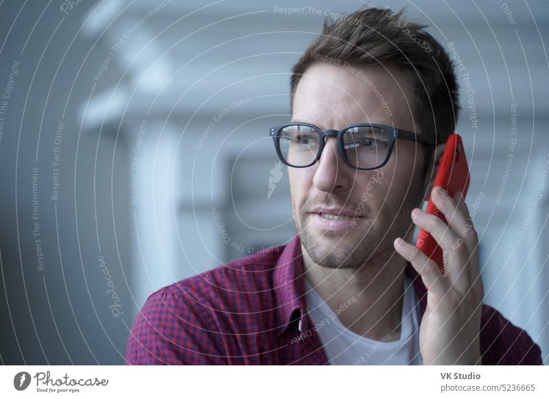 Thoughtful young German businessman in glasses having urgent conversation on mobile phone german austrian guy male telephone talking consultation discuss