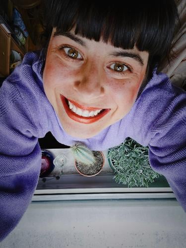 A woman stands with cactus at the window and grins euphorically into the camera Woman Grinning Window Euphoric Cactus surreal Excessive purple Window board