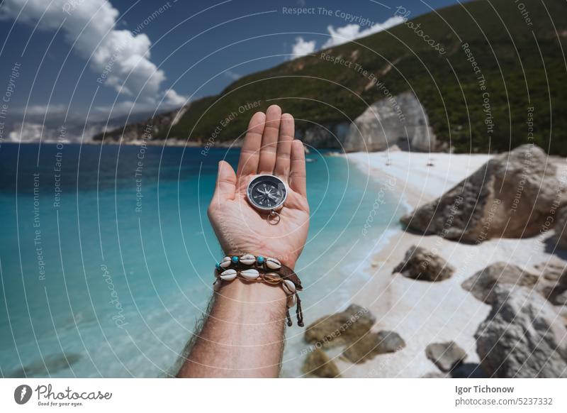 Hand holding a compass on the beach in background hand sea vacation travel equipment lost journey summer east hiking exploration direction guidance ocean