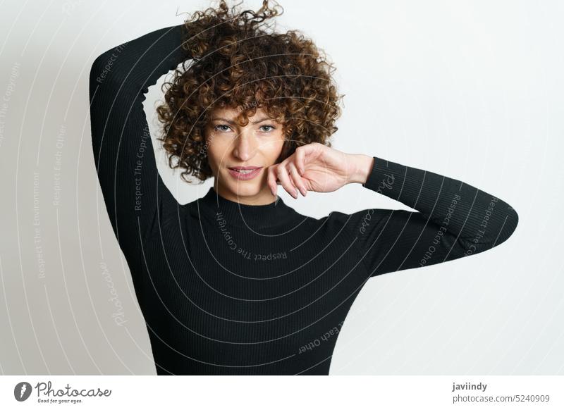 Happy female with curly hair smiling with hands near her head woman model positive illuminate light smile appearance glad hand behind head young optimist