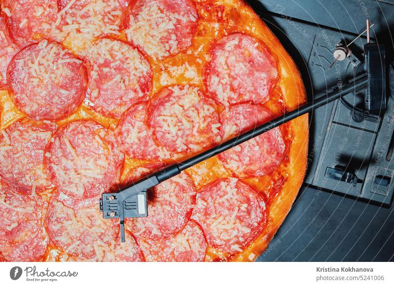 Italian pizza with salami as vinyl record rotating on turntable player.Pepperoni italian music party pepperoni food cheese fast hot slice crust melted