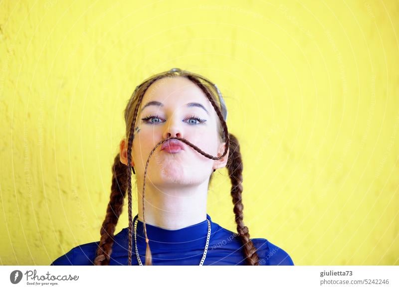 Cool teen girl styled with braids, cute kissing mouth and lady beard ;) in front of yellow background round portrait foolish Grimace Happiness Flirt teenager