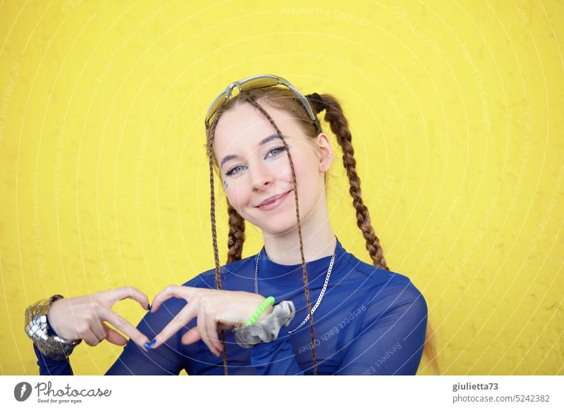 Stylish fashion girl with cool hairstyle and blue shirt showing heart with fingers on yellow background portrait Smiling Positive Peace Love Heart Happy