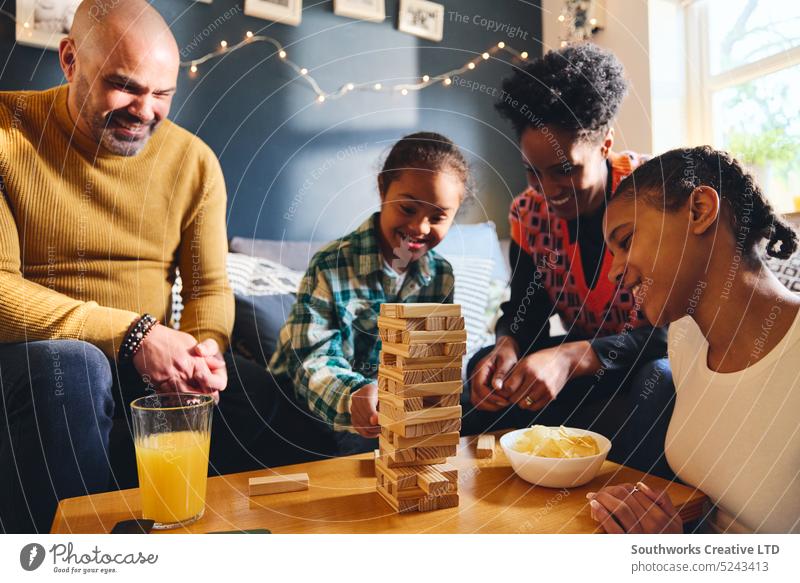 Boy with Down syndrome playing board game with family at home boy down syndrome multiracial lifestyle father mother girl togetherness weekend leisure fun son