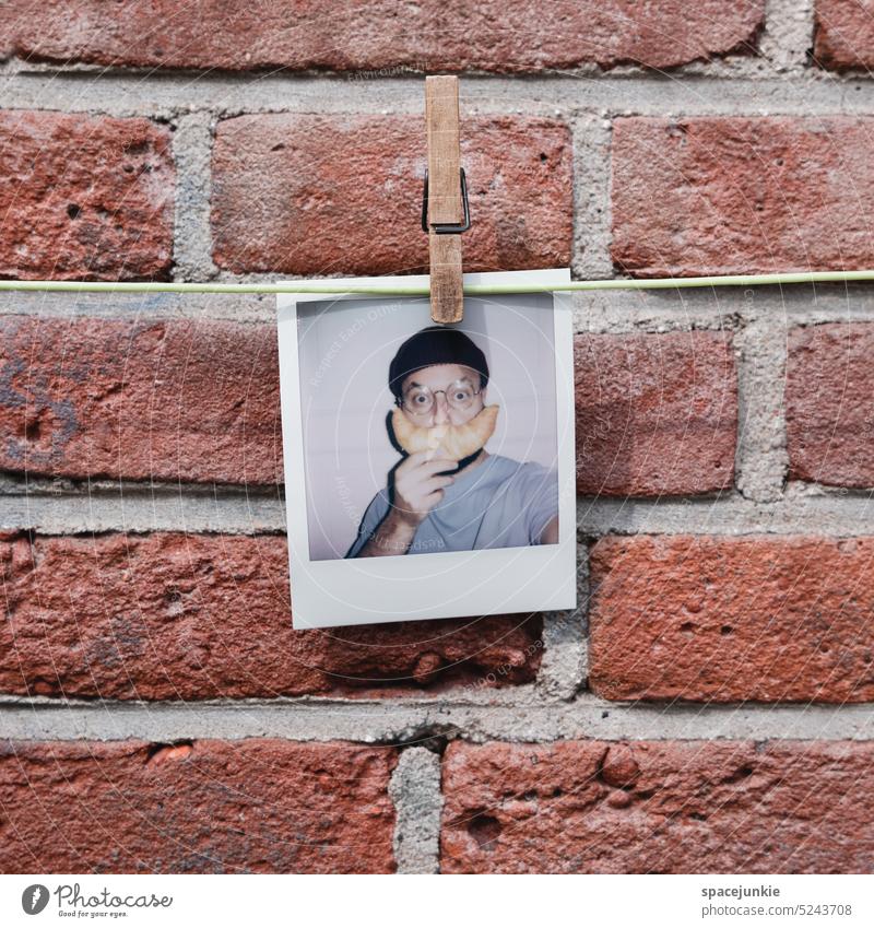 Polaroid Polaroid Style Wall (building) brick wall leash clothesline Holder Dry Man Cap Whimsical Humor Facial hair Croissant Eyeglasses Person wearing glasses