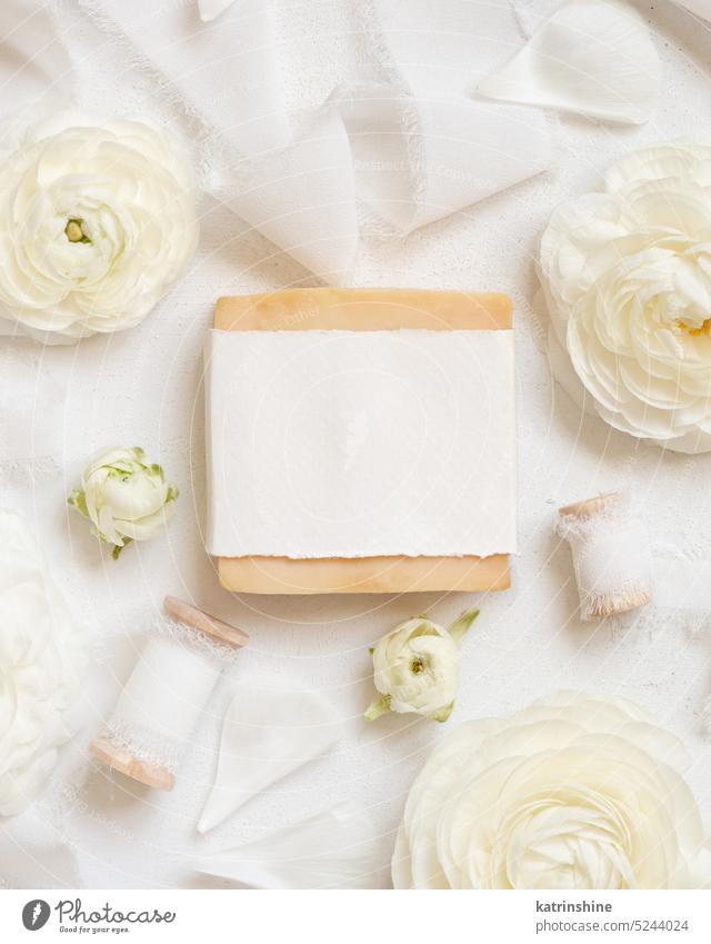 Handmade soap bar with blank label near cream roses and white ribbons top view, mockup flowers romantic silk valentine spring natural mothers day above pastel