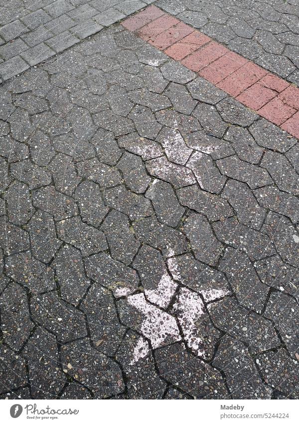 White faded painted stars on the gray composite pavement of a schoolyard after a graduation ceremony at the Niklas Luhmann Gymnasium in Oerlinghausen near Bielefeld in the Teutoburg Forest in East Westphalia-Lippe, Germany