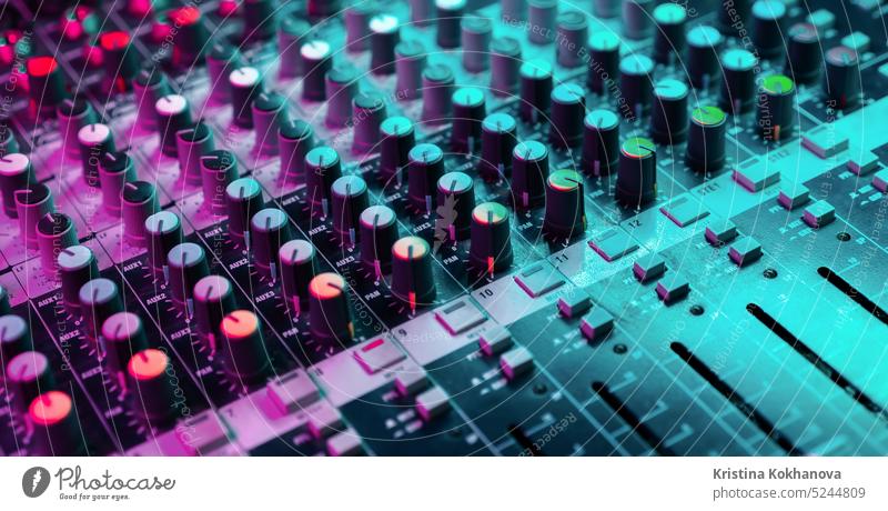 Close up of sound mixing console. Details of sound engineer room. Neon light dj audio mixer panel control digital equipment media studio technology desk