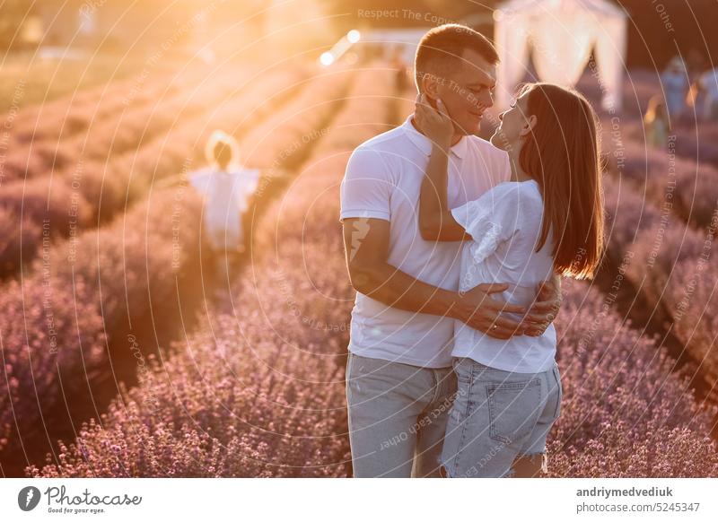 happy family day. young father, mother and child daughter are having fun together in the lavender field on sunset. happy couple with kid enjoy summer holiday vacation. family look
