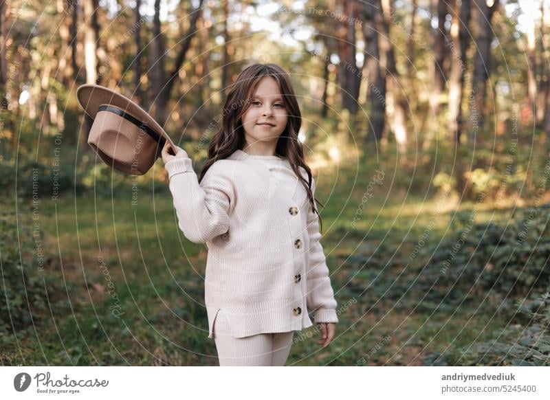 Portrait of beautiful little girl in hat looking at camera and smiling. Happy cute child having fun in park outdoors, enjoying childhood, be in good mood. Dream of child and happiness of child