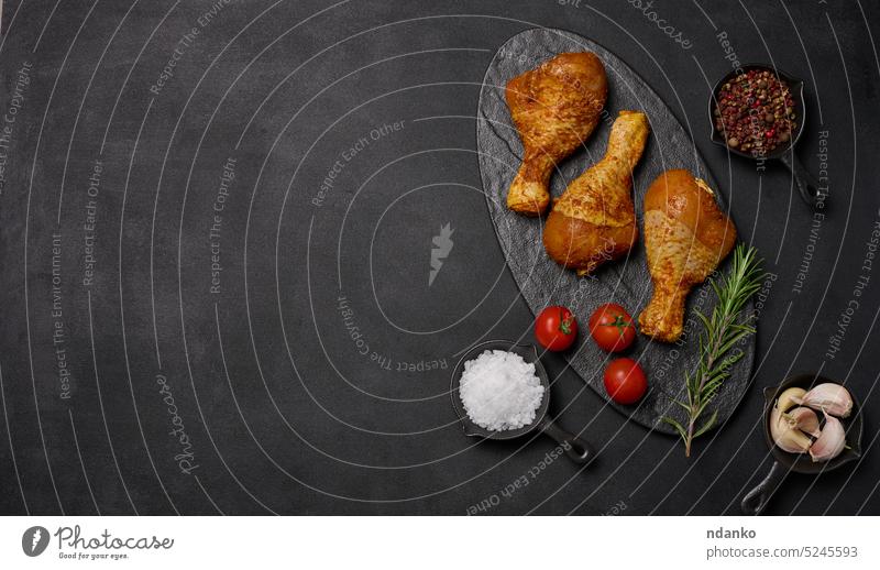 Raw chicken legs in spices on a black board, top view. Cooking with spices meat raw tomato pepper garlic dinner bird lunch above table salt meal food fresh