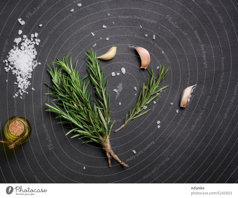 Scattered coarse white salt, peppercorns and rosemary sprigs on a black table, ingredients for cooking fish and meat garlic savory scent seasoning spice spicy