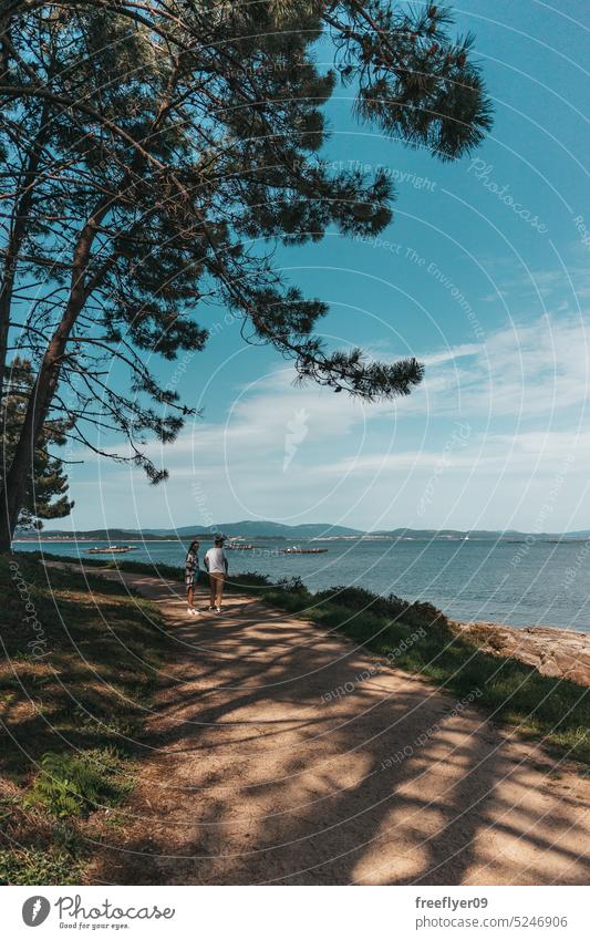 Young couple taking a walk near the ocean walking hiking peace slow life physical activity love copy space female dirt road path forest sea galicia pinecone