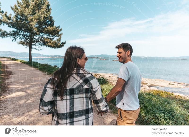 Young couple taking a walk near the ocean walking hiking peace slow life physical activity love copy space female dirt road path forest sea galicia pinecone