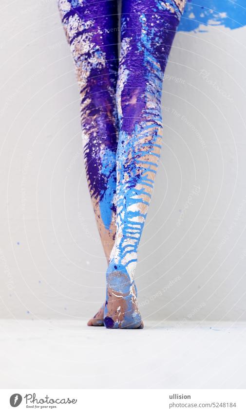 back view to beautiful legs and feet on tiptoe of a sexy young artistically abstract painted woman, ballerina with white, blue and purple and paint from behind