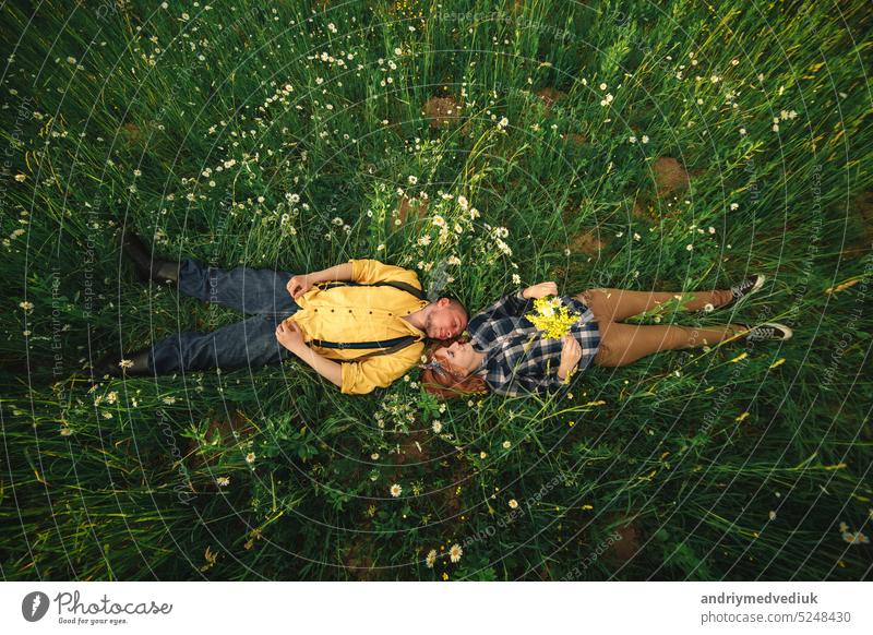 couple lying in a field of flowers. Happy couple lie in a flower. Romance, emotional and love scene. happy camomile romantic young grass woman female meadow