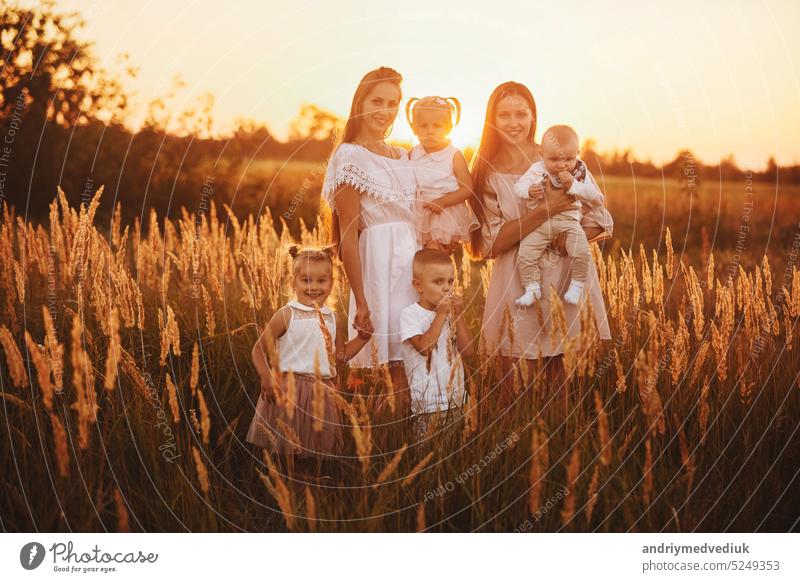 happy big gay family on sunset. Two young beautiful mothers and four little children are having fun together outdoors on summer sunny day in the park. happy childhood. mothers day
