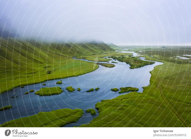Iceland. Aerial view on mountain, field and river. Landscape in Iceland at the day time. View from drone. Summer. Cloudy weather. Fresh grass on field. Travel and vacation image
