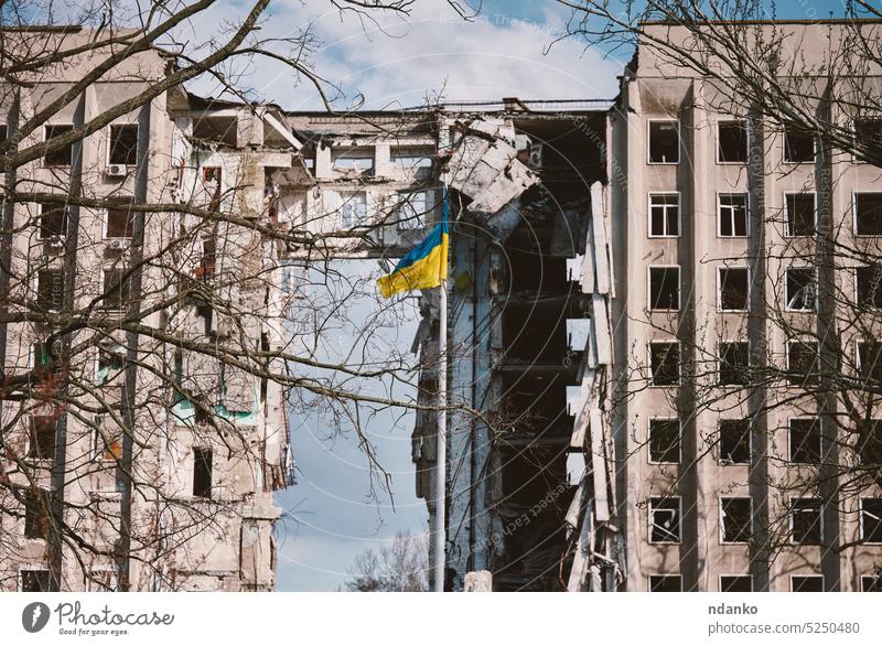 Flag of Ukraine against the background of a destroyed building in Ukraine. The building was destroyed by a Russian air bomb flag house invasion no people