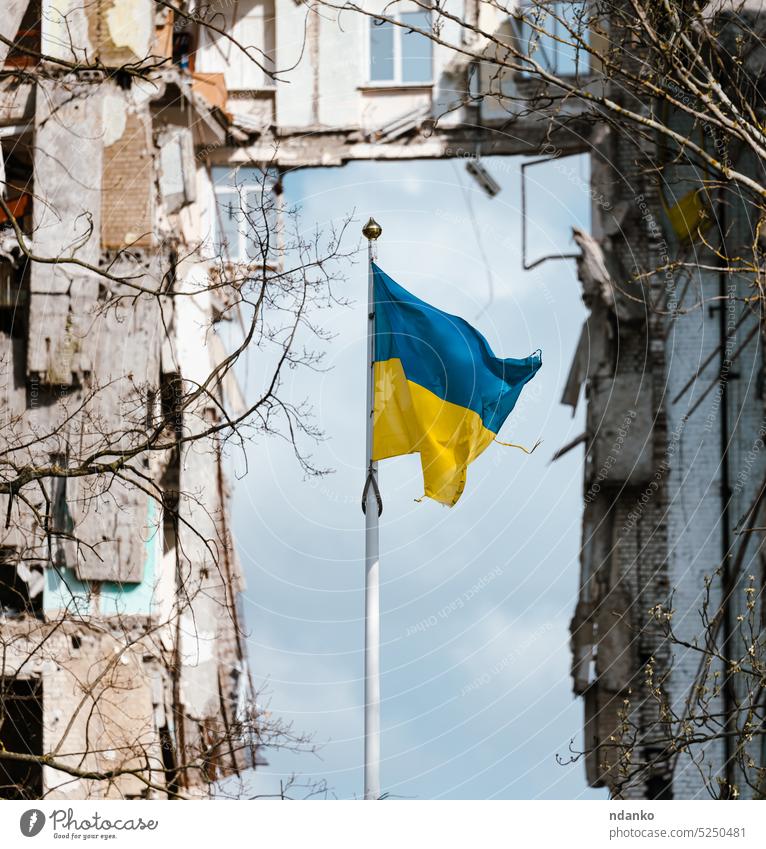 Flag of Ukraine against the background of a destroyed building in Ukraine flag yellow blue steadfast strong unbroken battered evolving invasion ukraine war