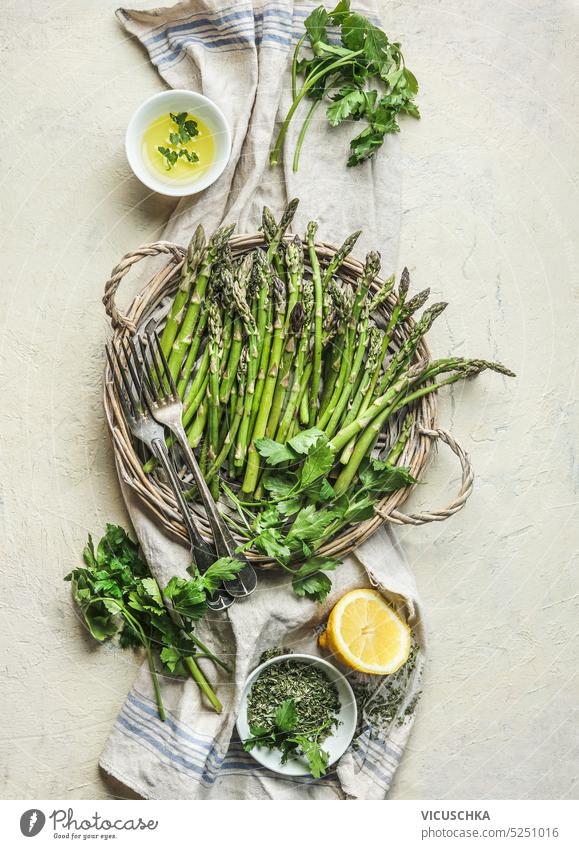 https://www.photocase.com/photos/5251016-green-asparagus-bunch-on-wicker-tray-on-white-table-background-with-cooking-ingredients-herbs-olive-oil-and-seasonings-in-bowls-top-view-photocase-stock-photo-large.jpeg