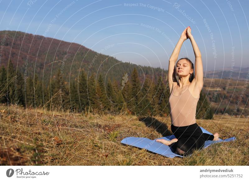 Young girl doing yoga fitness exercise outdoor in beautiful mountains landscape. Morning sunrise, Namaste Lotus pose. Meditation and Relax. Healthy Lifestyle.
