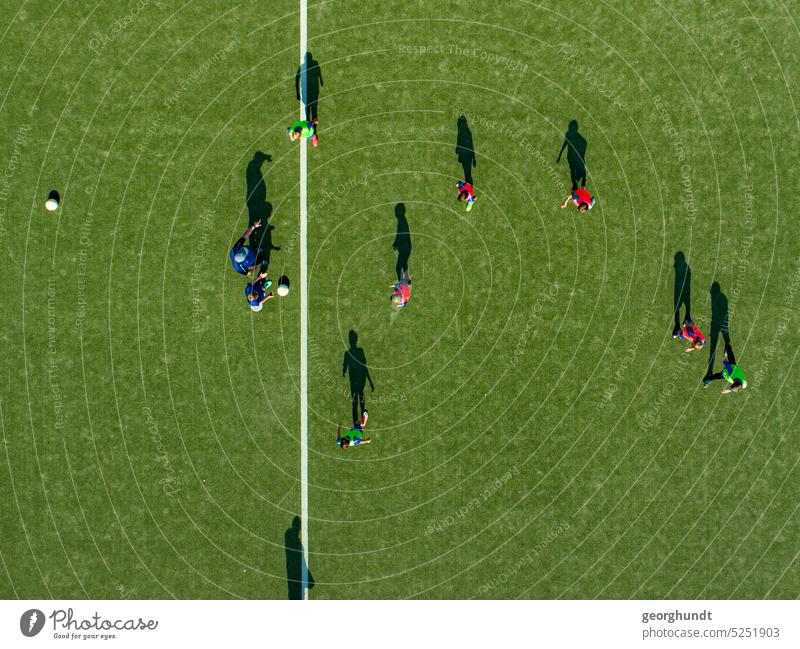 Soccer players in training with several balls on a field with artificial turf. View strictly from above. The center line can be seen. Foot ball Player