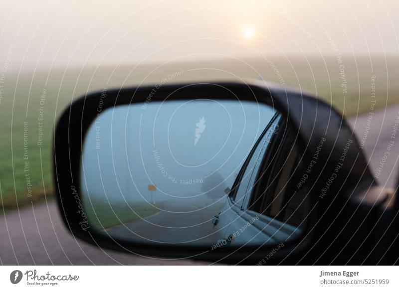 A car is driving along a road, the sky and the road are reflected in the side mirror. Side mirror Driving Mirror Street Sky Transport Fog Vehicle