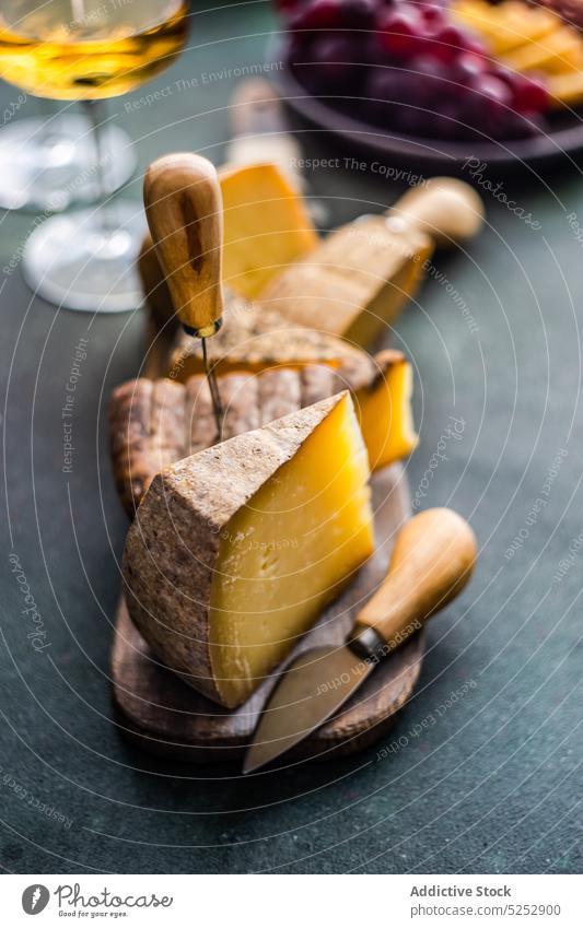 Cheese variety on the wooden cutting board goat table background wine dairy assortment food meal fresh stoneware glass cheese grape plate slice ripe knife